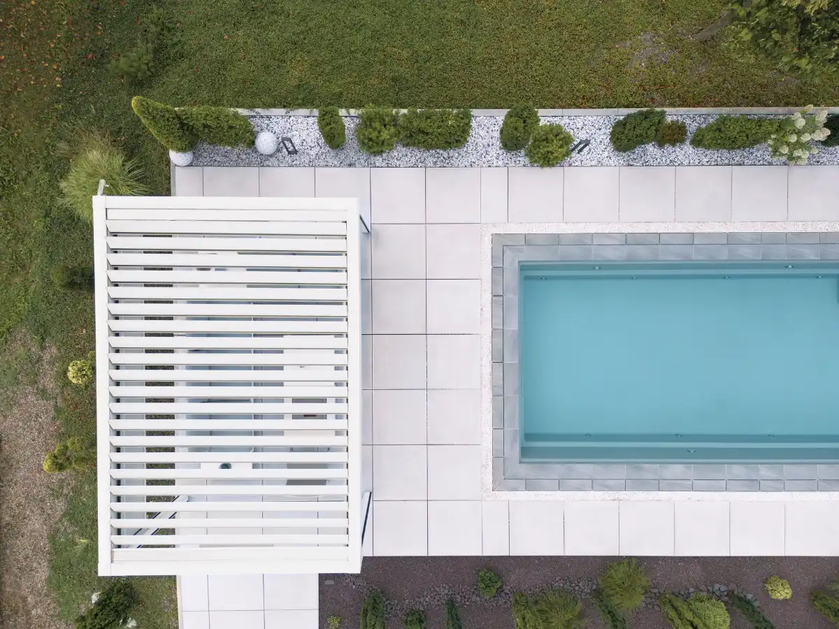 Lamellendach neben einem Pool mit hellblauem Wasser
